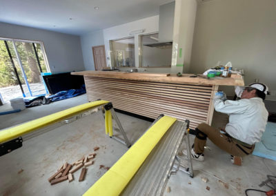 Local Japanese carpenter at work installing cedar countertop inside Hakuba snowboard factory workshop.